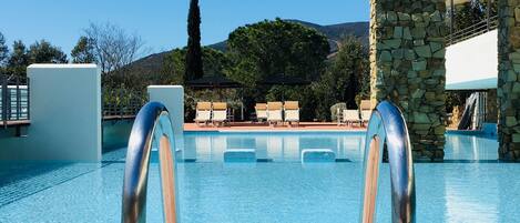 A clear blue pool with a stone archway and metal poolside railings.