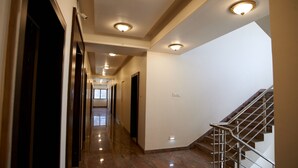 Passadís d'hotel amb sòl de marbre polit, escala amb barana metàl·lica i llums encastades al sostre.