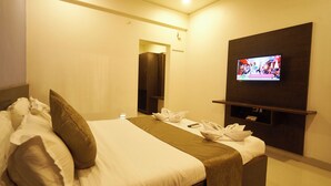 Una habitació d'hotel amb un llit, una televisió penjada a la paret i una taula petita amb un comandament a distància.