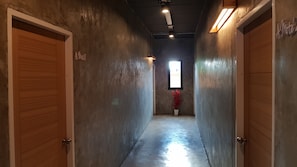 A hallway with concrete walls, wooden doors, and a potted plant. - A-Mote Loft at Phitsanulok (Phitsanulok)