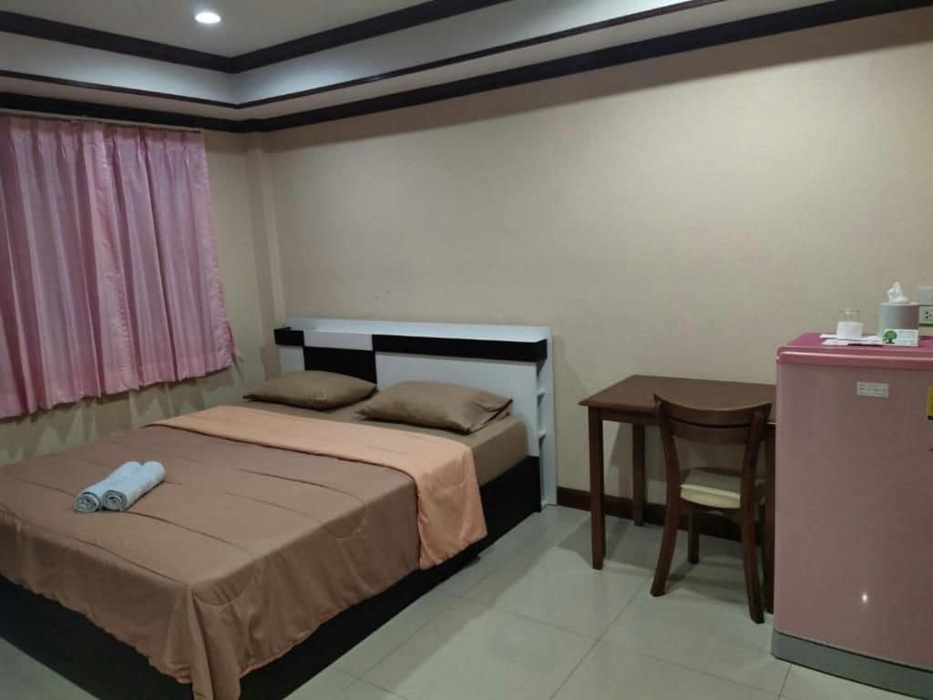 Un dormitorio con cama, escritorio, silla y refrigerador.