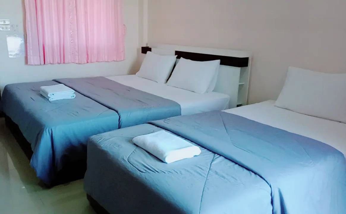 A hotel room with two single beds, each with a blue bedspread and a white pillow.
