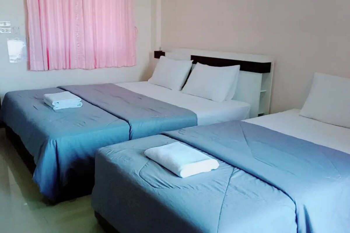A hotel room with two single beds, each with a blue bedspread and a white pillow.