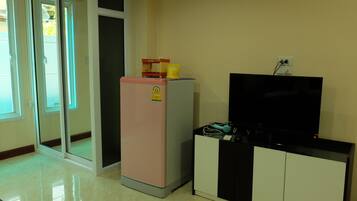 A compact living space with a refrigerator, a flat-screen TV, and a cabinet.