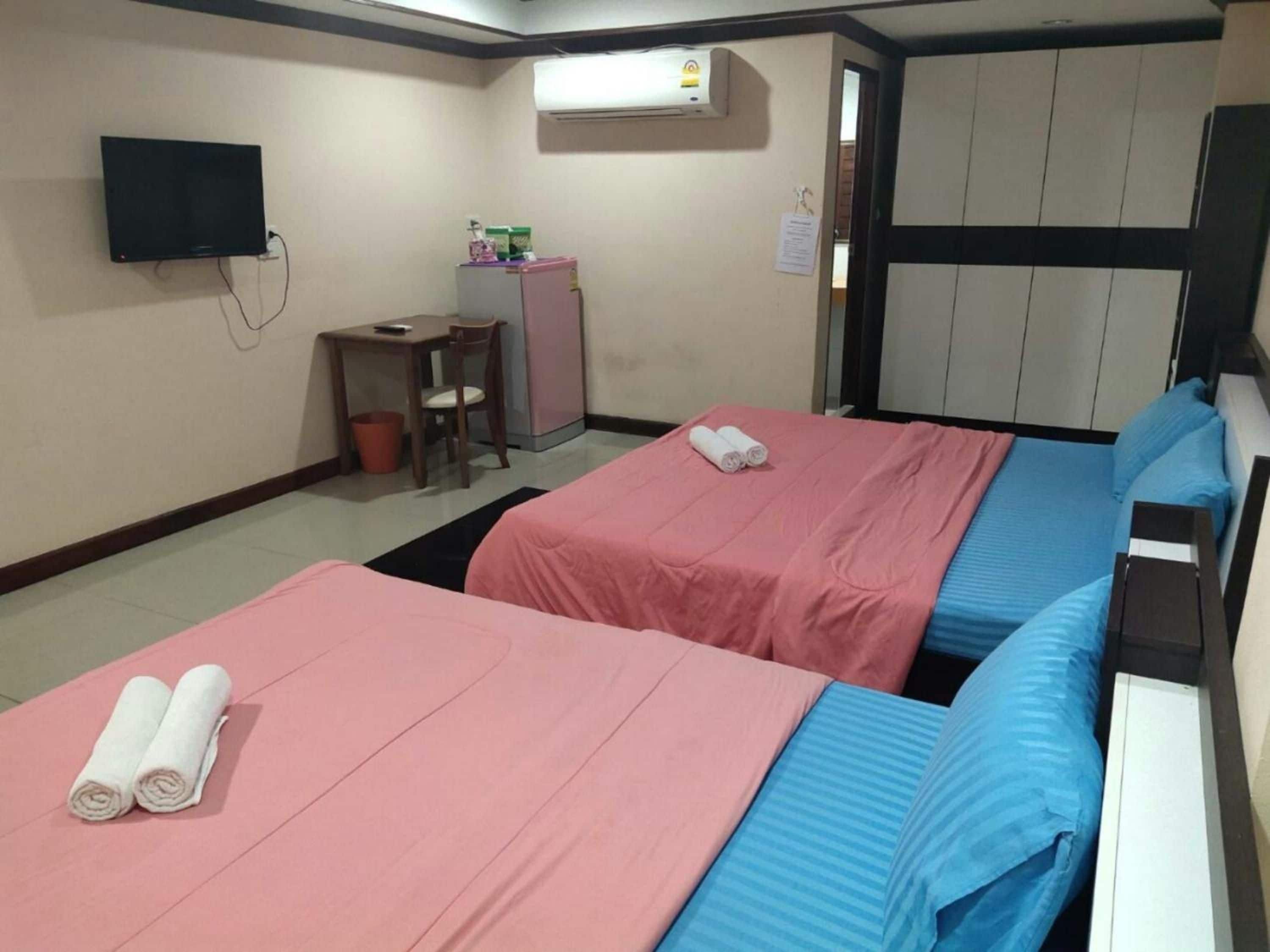 Habitación de hotel con dos camas, un escritorio, una silla, un televisor y un equipo de aire acondicionado.