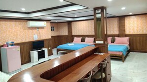 A hotel room with two beds, a wooden desk, a TV, and an air conditioning unit. - Tree House Chachoengsao (Chachoengsao)