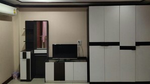 A modern room with a flat-screen TV, built-in cabinets, and a ceiling light fixture. - Tree House Chachoengsao (Chachoengsao)