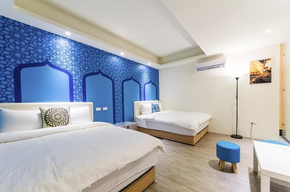 A hotel room with two beds, a blue patterned wall, a standing lamp, and a small table. - X Square (Luodong)