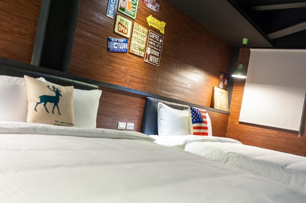 Une chambre d’hôtel avec un mur en bois, un lit avec une literie blanche et divers éléments décoratifs, notamment un coussin à l’effigie d’un cerf et un coussin orné du drapeau américain.