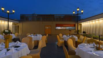An outdoor dining area with tables set for a meal, a sign reading "TERRACCO", and a wooden door in the background.