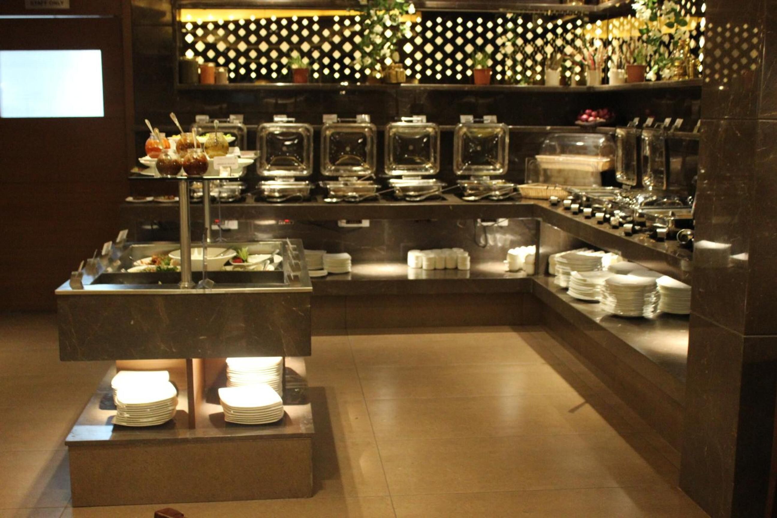 Un buffet avec différents récipients contenant de la nourriture et une pile d’assiettes disposées en présentation.