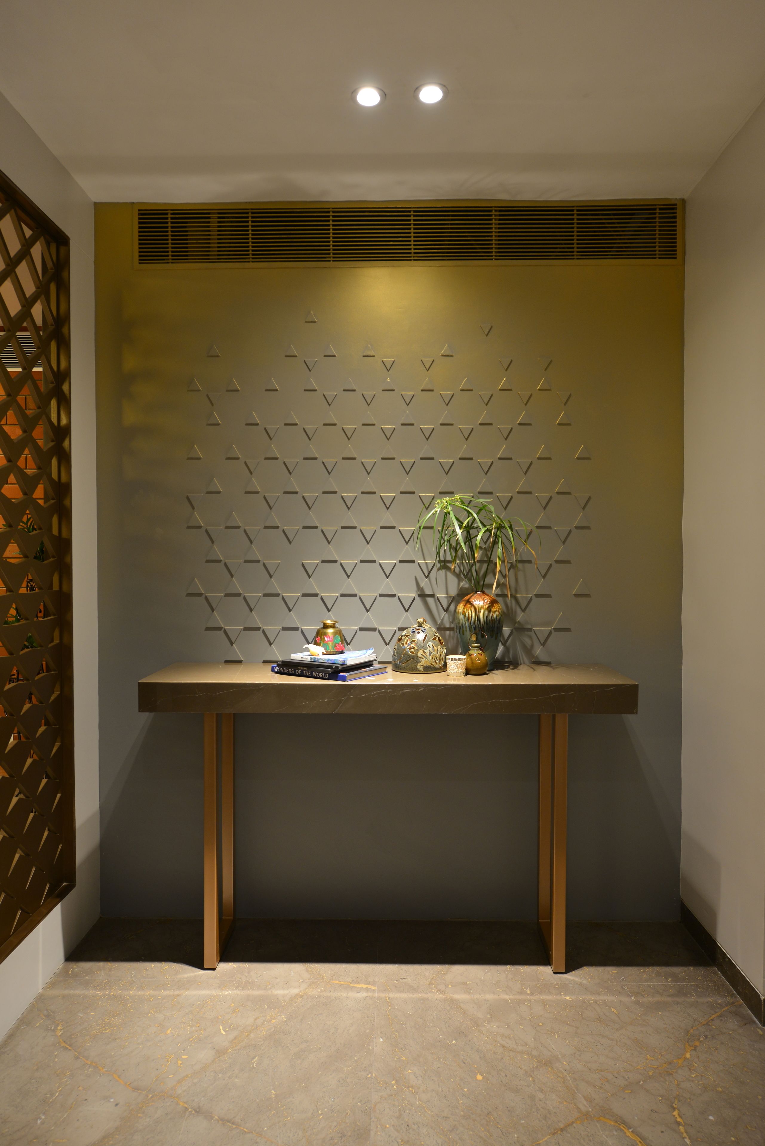 Un comptoir d’accueil agrémenté d’un mur décoratif, d’une plante et de quelques livres.