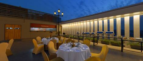 A rooftop restaurant with outdoor seating, a terrace with a view, and a sign for 'TERRACO'.