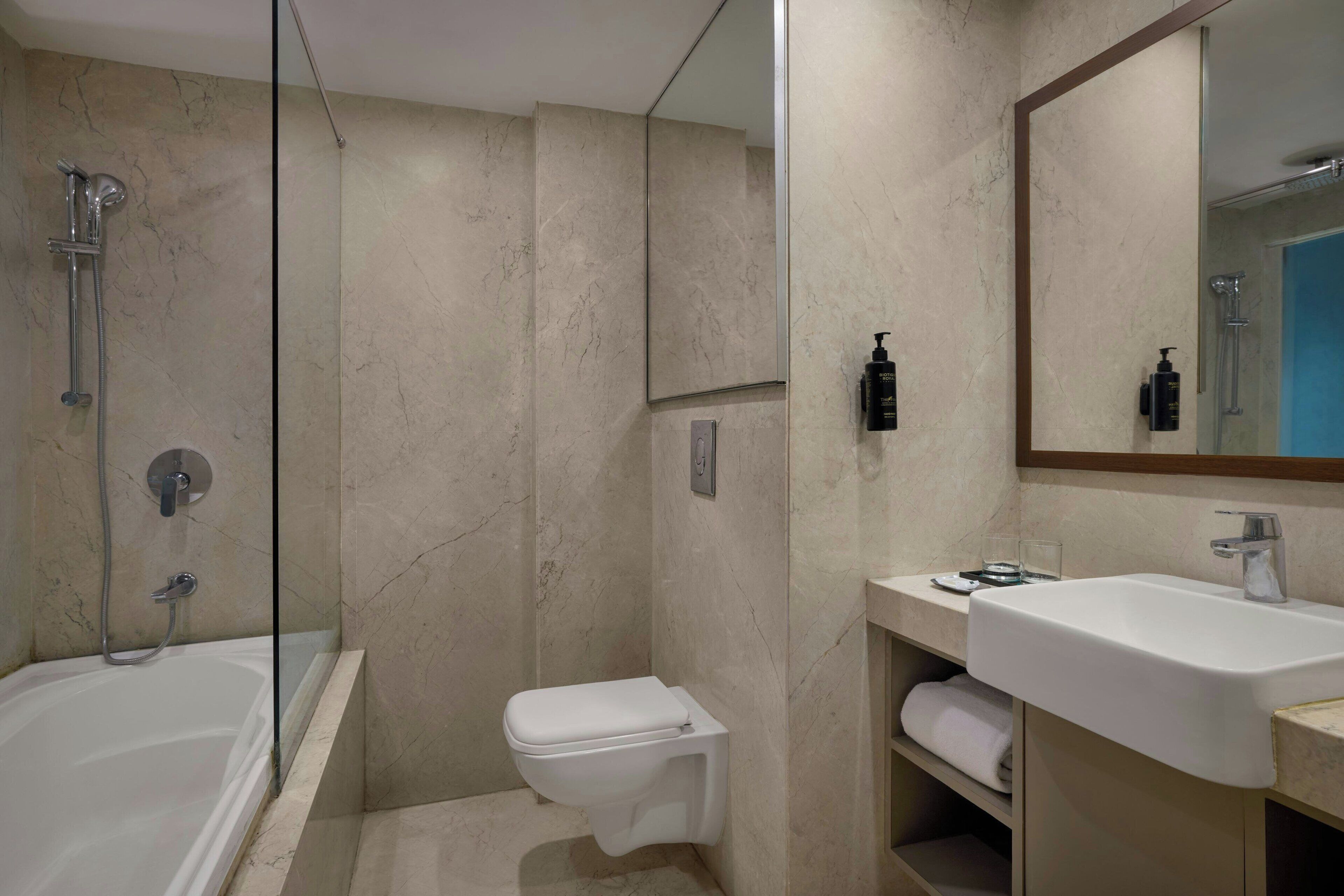 A modern bathroom with a glass-enclosed shower, a white toilet, and a sink with a mirror above.