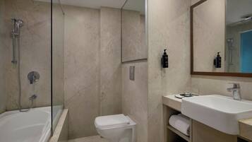 A modern bathroom with a glass-enclosed shower, a white toilet, and a sink with a mirror above.