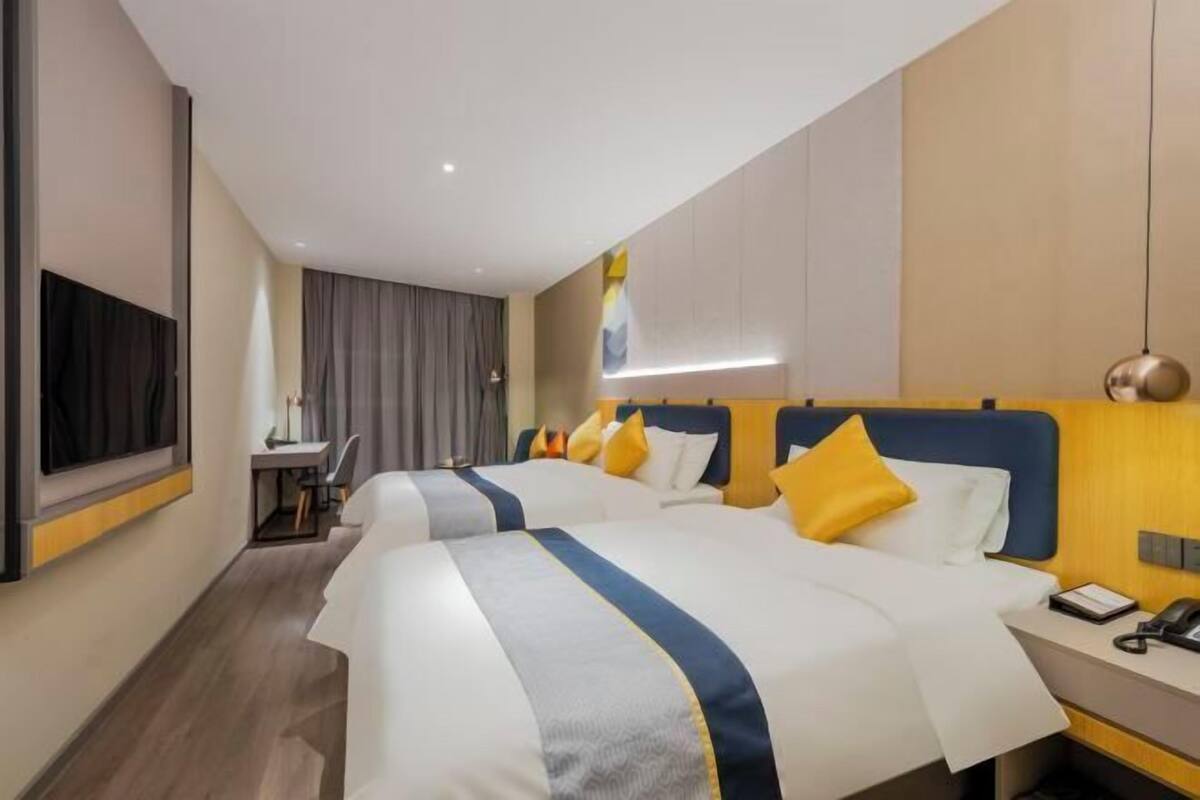 A hotel room with two beds, a desk, and a TV.