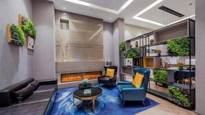 A modern living room with a fireplace, seating, and a bookshelf with plants. - Homeinn Selected Hotel (Chongqing Jiefangbei Area Hong Ya Dong Pedestrian Street) (Chongqing)