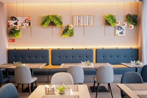 A restaurant interior with booths, tables, and hanging plants.