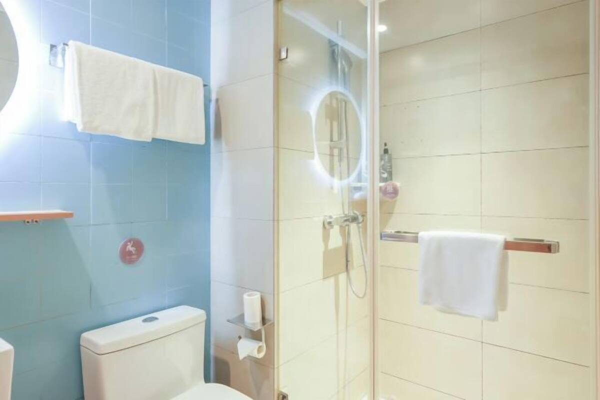A bathroom with a toilet, a shower, and a towel rack.