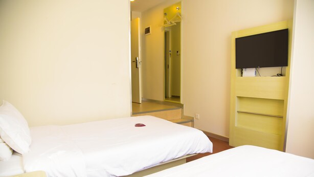 Una habitación de hotel con dos camas, televisión y espejo.
