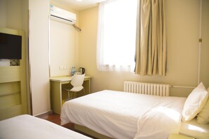 A hotel room with two beds, a desk, a chair, a radiator, and a television mounted on the wall. - Hanting Hotel (jiuquan Changxing Electrical Equipm (Jiuquan)