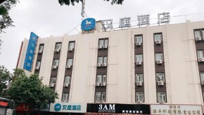 Un edificio de hotel con varios pisos, unidades de aire acondicionado y varios comercios en la planta baja.
