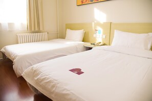 A hotel room with two single beds, a bedside table with a phone, and a radiator. - Hanting Hotel (jiuquan Changxing Electrical Equipm (Jiuquan)