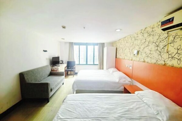 Una habitación de hotel con dos camas individuales, un sofá, un escritorio y un televisor.
