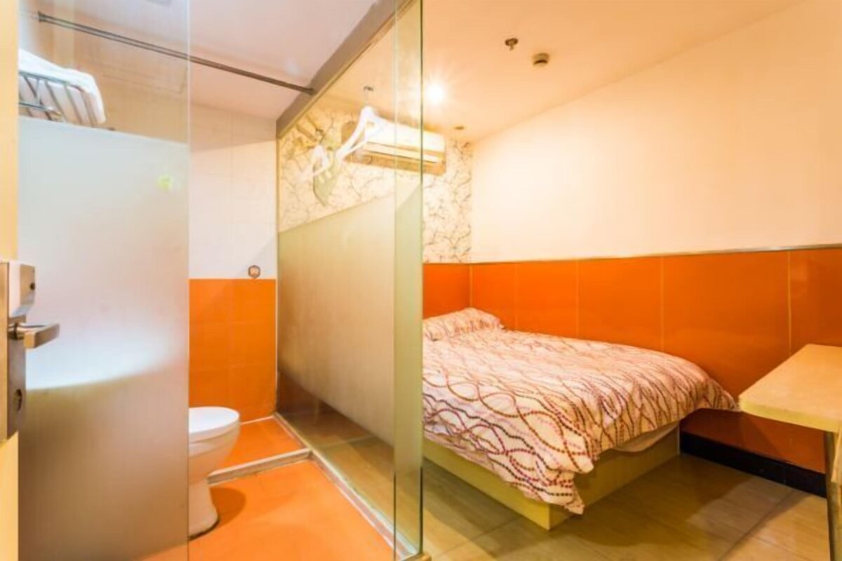 Una habitación pequeña y funcional con cama, inodoro y zona de ducha.