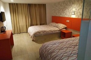 Una habitación de hotel con dos camas, un televisor sobre un mueble, una cafetera y una cortina.
