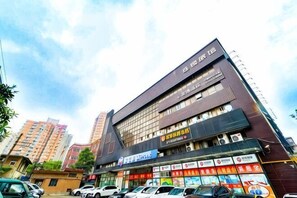Un edificio de varios pisos con un letrero llamativo en la parte superior y varios comercios en la planta baja.
