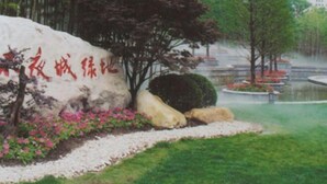 A landscaped area with a large rock featuring red text, surrounded by greenery and a small water feature. - 99 Inn (Shanghai Railway Station No.1 branch) (Shanghai)