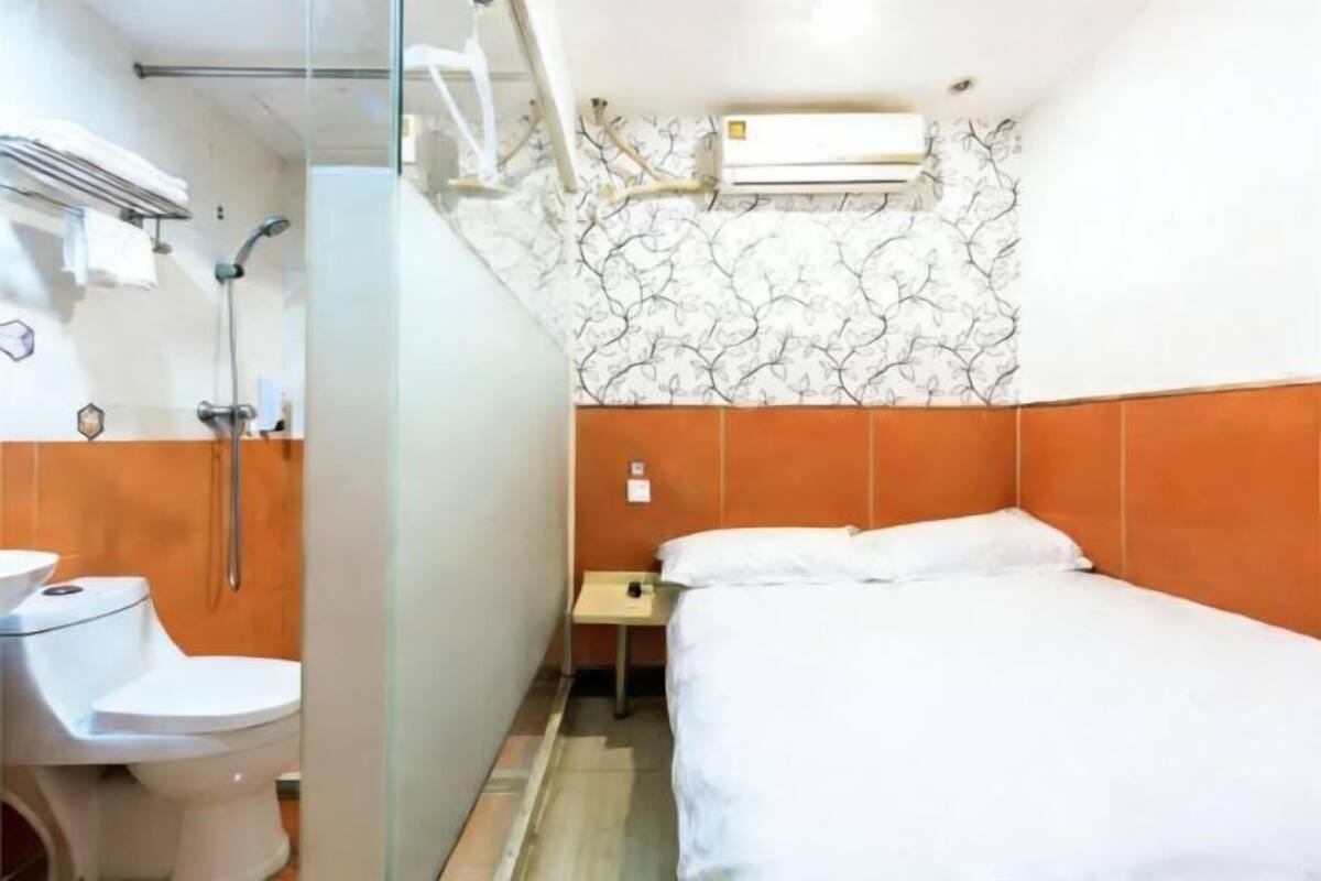 A small hotel room with a shower, toilet, and bed.