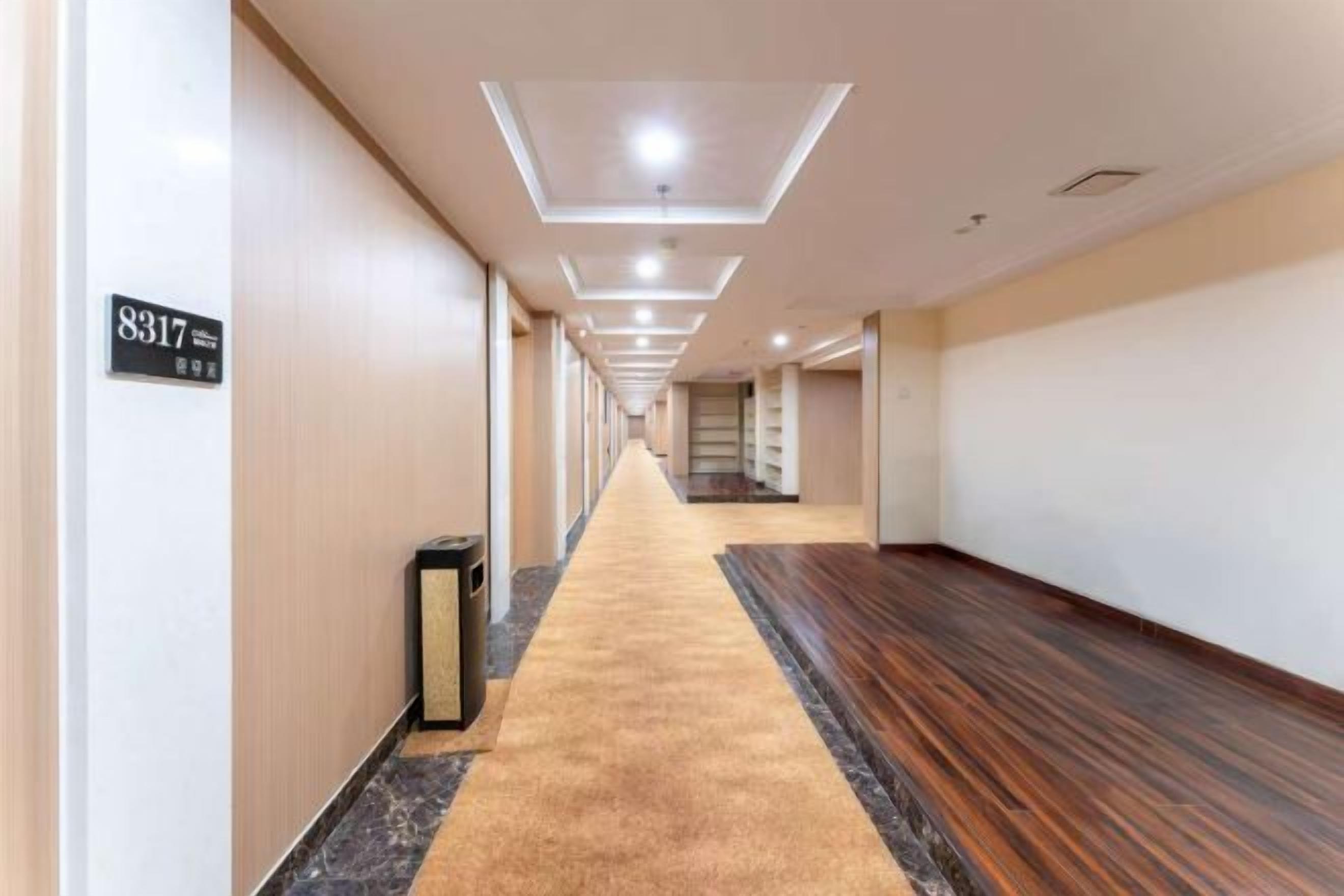 A hotel corridor with a carpeted floor, a trash bin, and a sign indicating room number 8317.