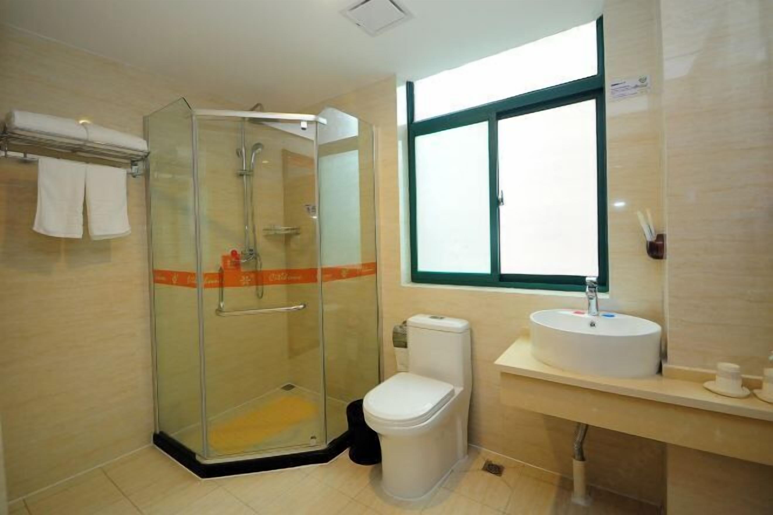A modern bathroom with a glass-enclosed shower, a toilet, a sink, and a window providing natural light.