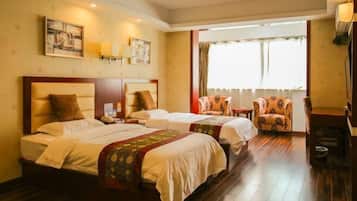 A hotel room with two beds, a sitting area with a chair, and a window with curtains.