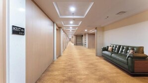 Passadís d'hotel amb terra de moqueta, un sofà de pell verda i un senyal que indica la habitació 8317.