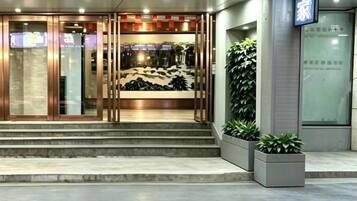 A hotel entrance with a glass door, steps leading up to it, and a sign above the door.