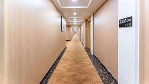 Passadís llarg i estret d'un hotel amb sòl de moqueta i un senyal que indica la habitació 8305.
