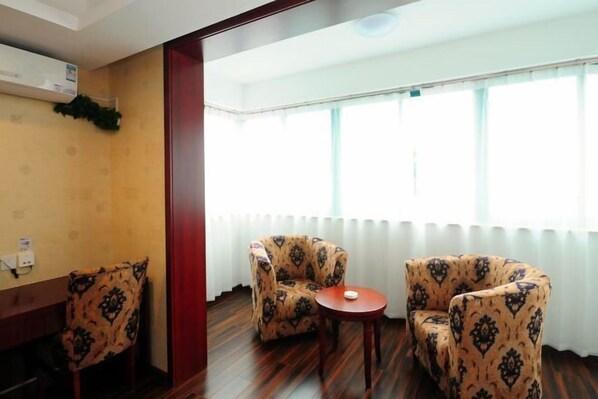 A room with two patterned armchairs, a small wooden table, and a window with blinds.