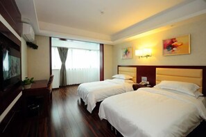 A hotel room with two beds, a desk, a chair, and a television.