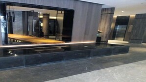 Un interior moderno con piso negro reflectante, una mesa de madera y un panel de vidrio.