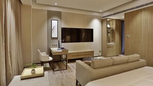 Habitación de hotel moderna con una cama grande, un escritorio con silla, un televisor de pantalla plana y un espejo amplio.
