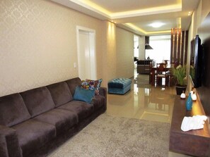 Apartamento família, vários quartos, suíte, vista para a cidade | Sala de estar | TV de tela plana