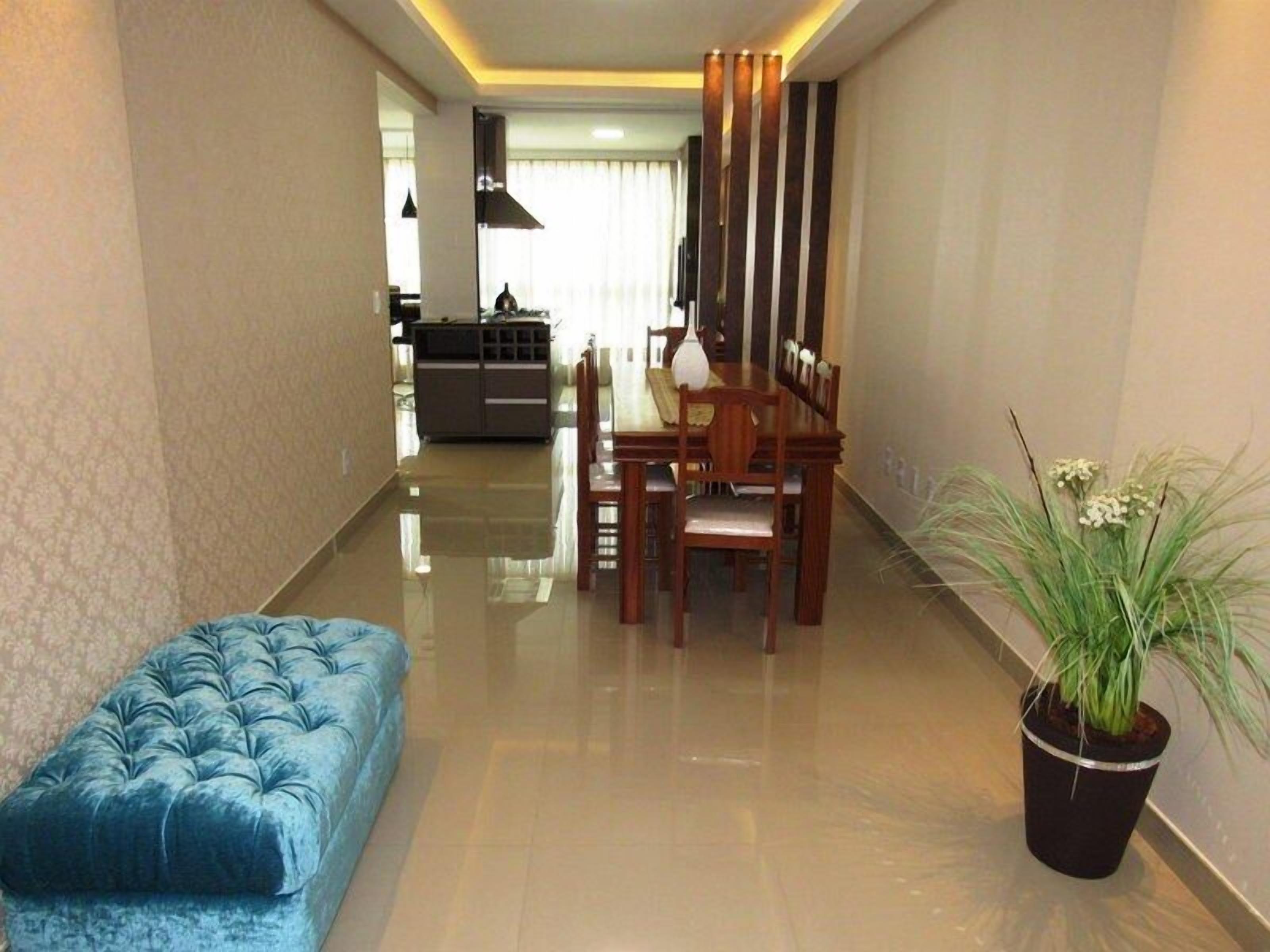 A modern living room with a blue sofa, a dining area with wooden furniture, and a potted plant.
