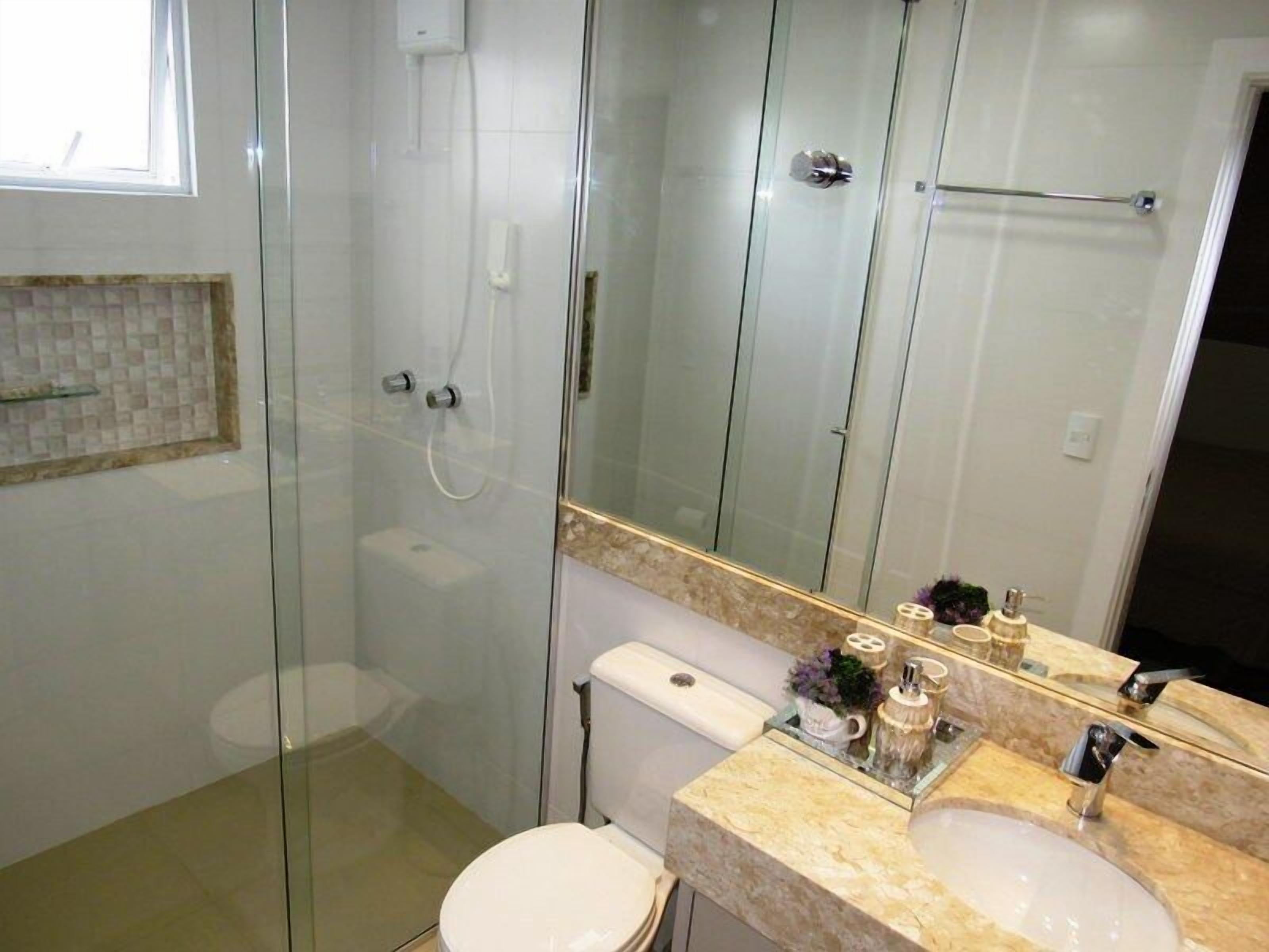 A modern bathroom with a glass-enclosed shower, a toilet, and a vanity with a sink and mirror.