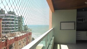 A balcony with a view of the sea, a microwave, and a whiteboard on the wall. - Apartamento a 200m do Mar BCHost 17 (Itapema)