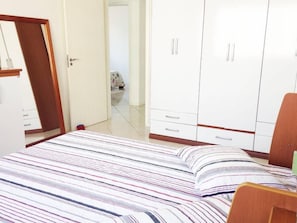 Un dormitorio con cama, armario y puerta que da a otra habitación.