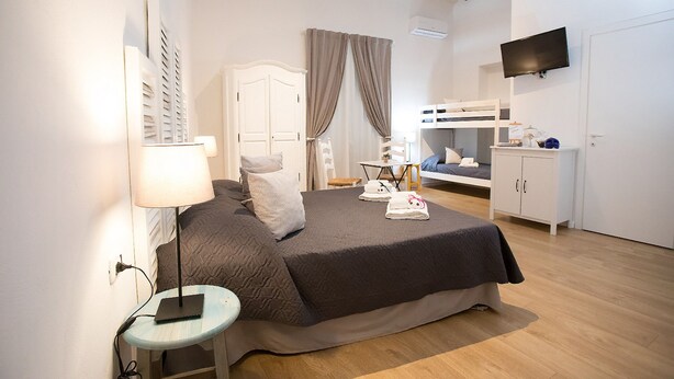 A bedroom with a bed, bedside table, lamp, wardrobe, and a television. - Quartino Napoletano (Naples)
