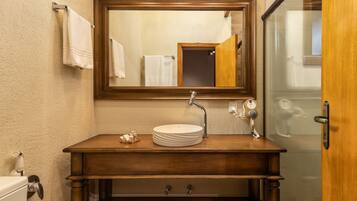 A bathroom with a wooden vanity, a round sink, a mirror, and a towel rack.